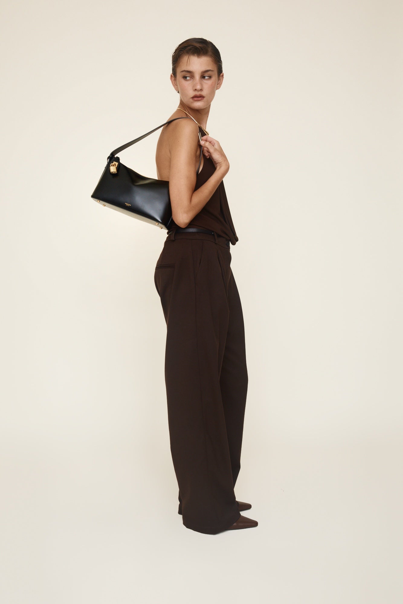 Woman holding a Gold Black Hobo Shoulder Handbag against a plain background