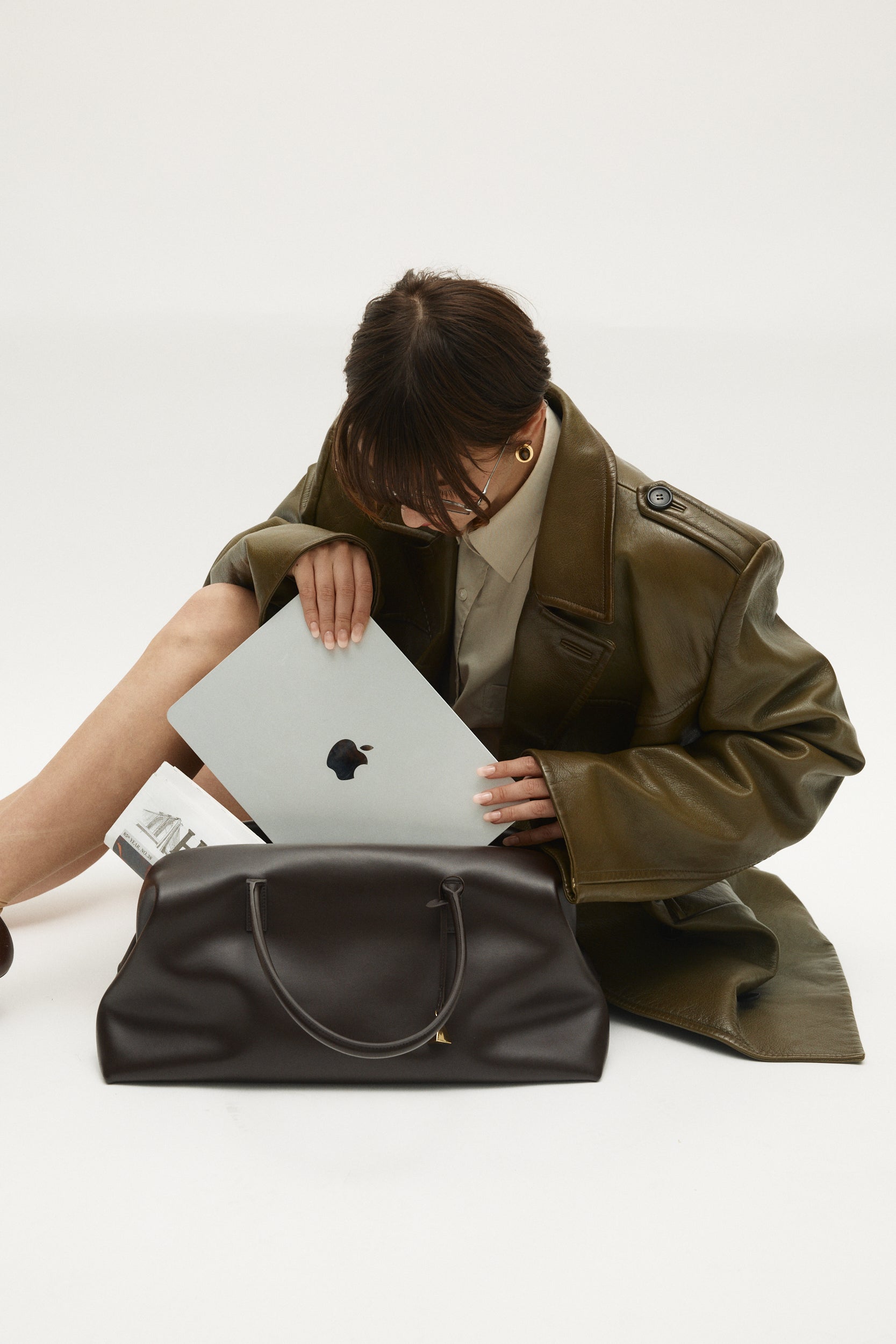 Person holding a laptop next to a Chocolate Club Large Handbag on a white background