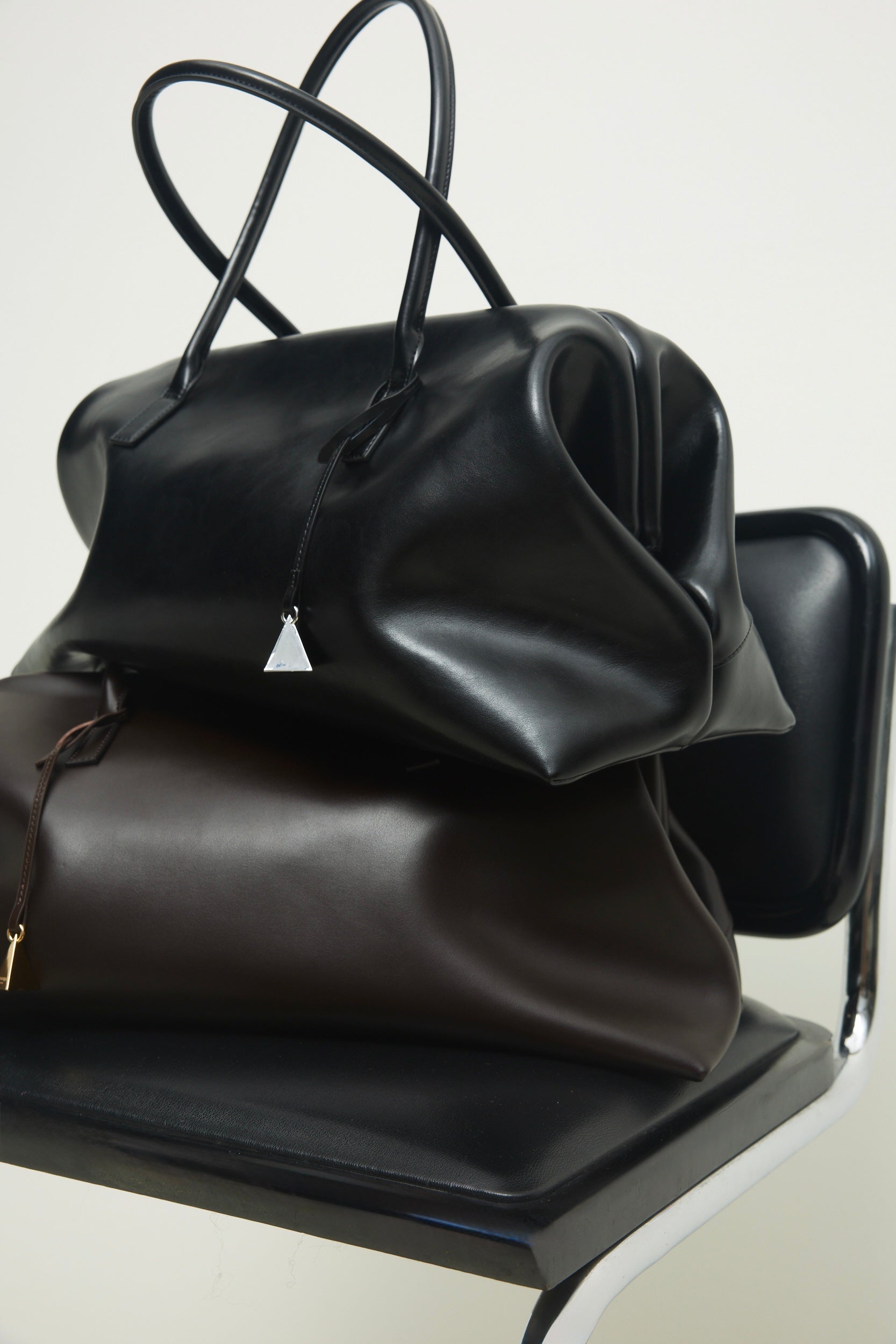 Three Black Club Large Handbags on a chair with a white background