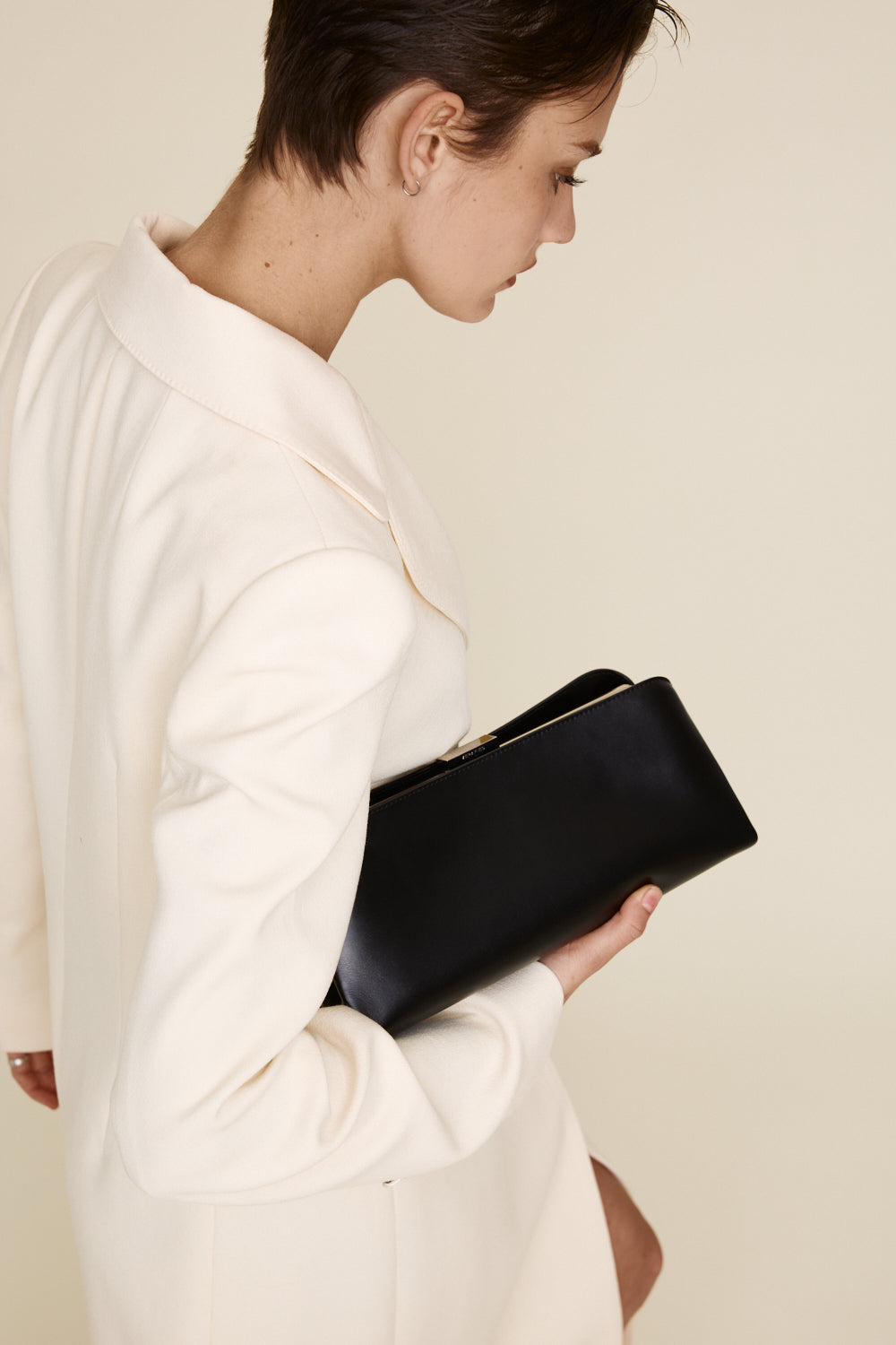 Woman holding a Silver Noir Éclair Clutch Shoulder Handbag (Black) against a plain background