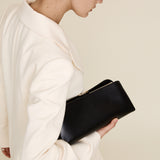 Woman holding a Silver Noir Éclair Clutch Shoulder Handbag (Black) against a plain background