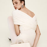 Woman in a white off-shoulder dress holding a matching Silver Ivory Éclair Bag: White Clutch Handbag against a plain background