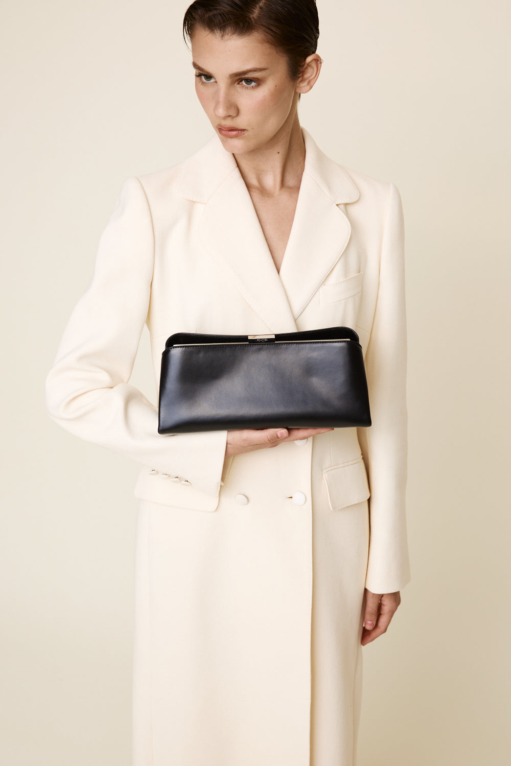 Woman holding a Silver Noir Éclair Clutch Shoulder Handbag (Black) against a plain background