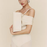 Woman in a beige off-shoulder dress holding a matching Silver Ivory Éclair Bag: White Clutch Handbag against a plain background