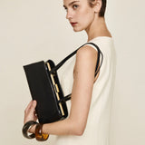 Woman holding a Gold Noir Éclair Clutch Shoulder Handbag (Black) against a plain background