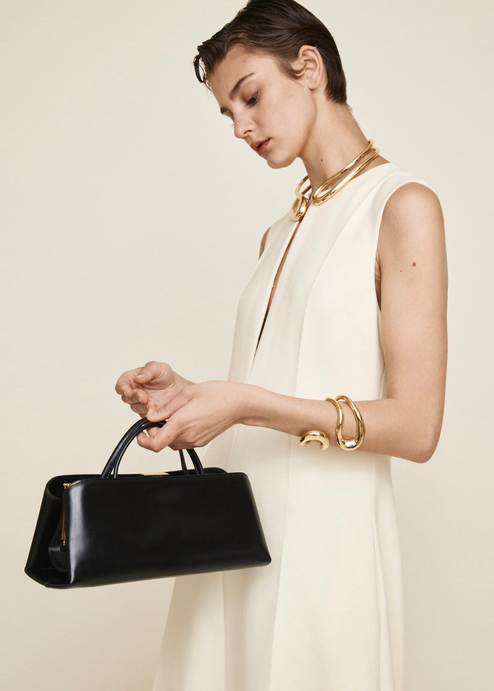 Woman holding a Gold Noir Éclair Clutch Shoulder Handbag (Black) against a plain background