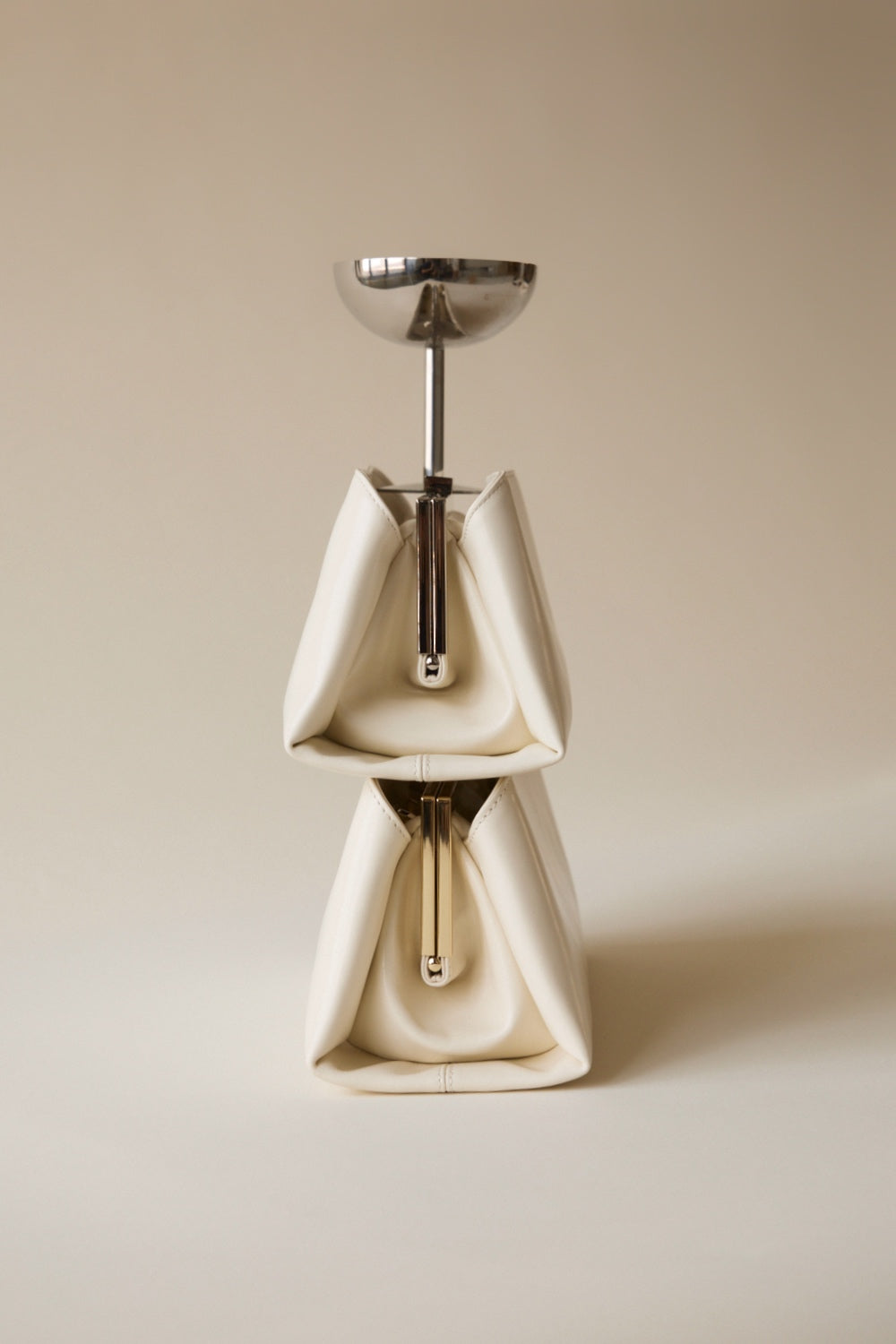 Ceramic coffee grinder with metallic top with two Gold Ivory Éclair Bags: White Clutch Handbags on a beige background