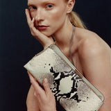 Woman holding a patterned clutch against a dark background