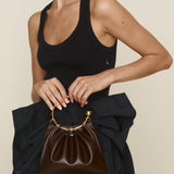 Person holding a Chocolate Circle Ring Mini Handle Bag with a plain background