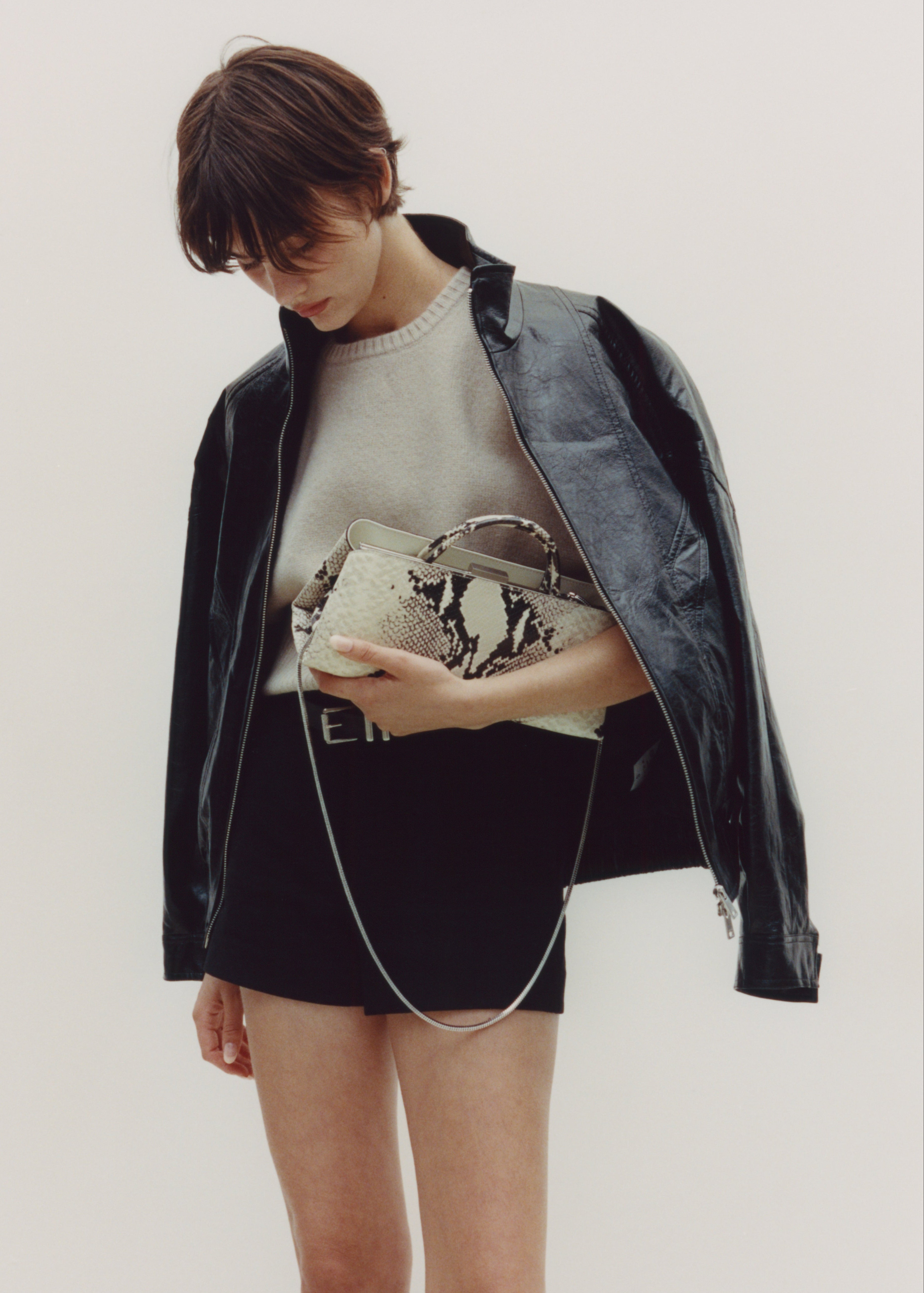 Person holding a Python Éclair Clutch Shoulder Handbag against a plain background