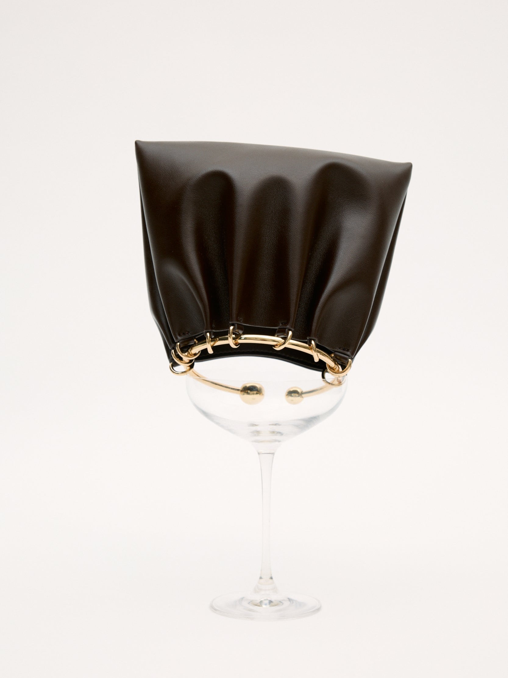 Black cocktail glass with a Chocolate Circle Ring Mini Handle Bag on a white background