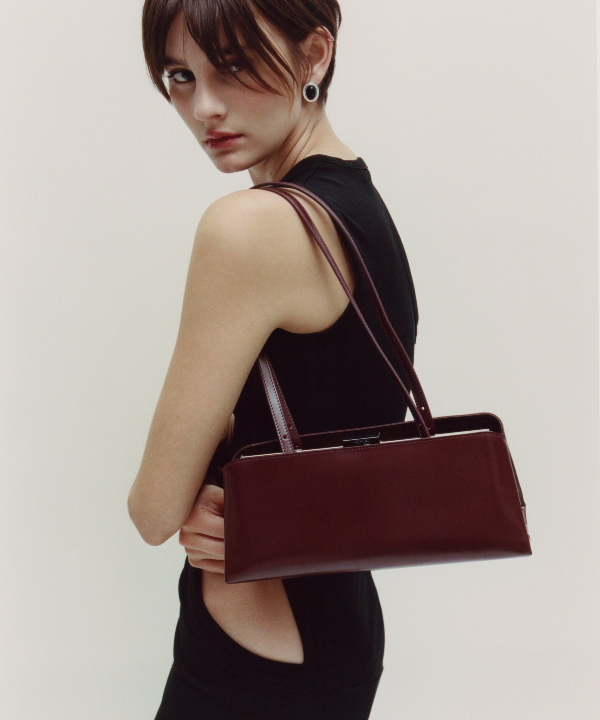 Woman holding a Burgundy Clutch Shoulder Handbag against a plain background