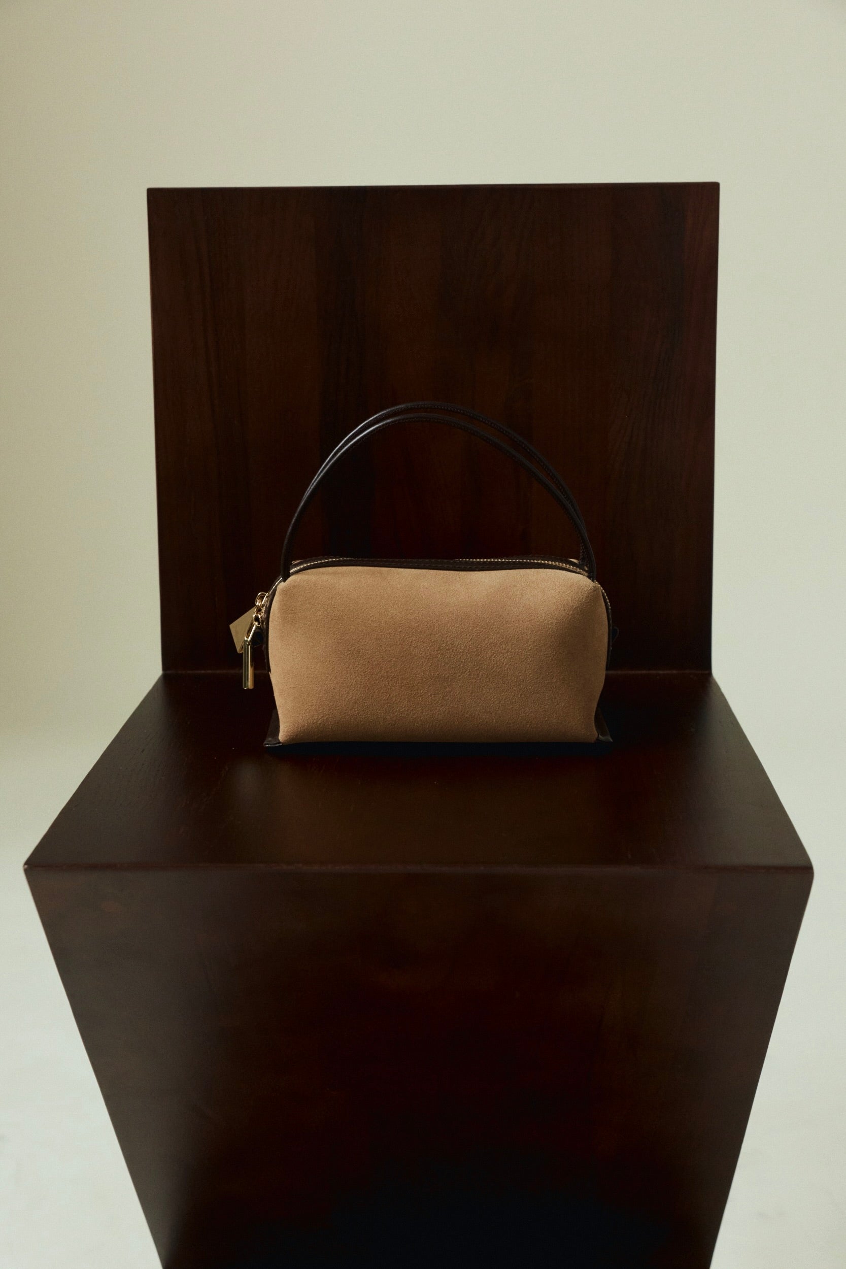 Verafied New York Gold Suede Café Mini Handbag on a dark wooden stand against a plain background
