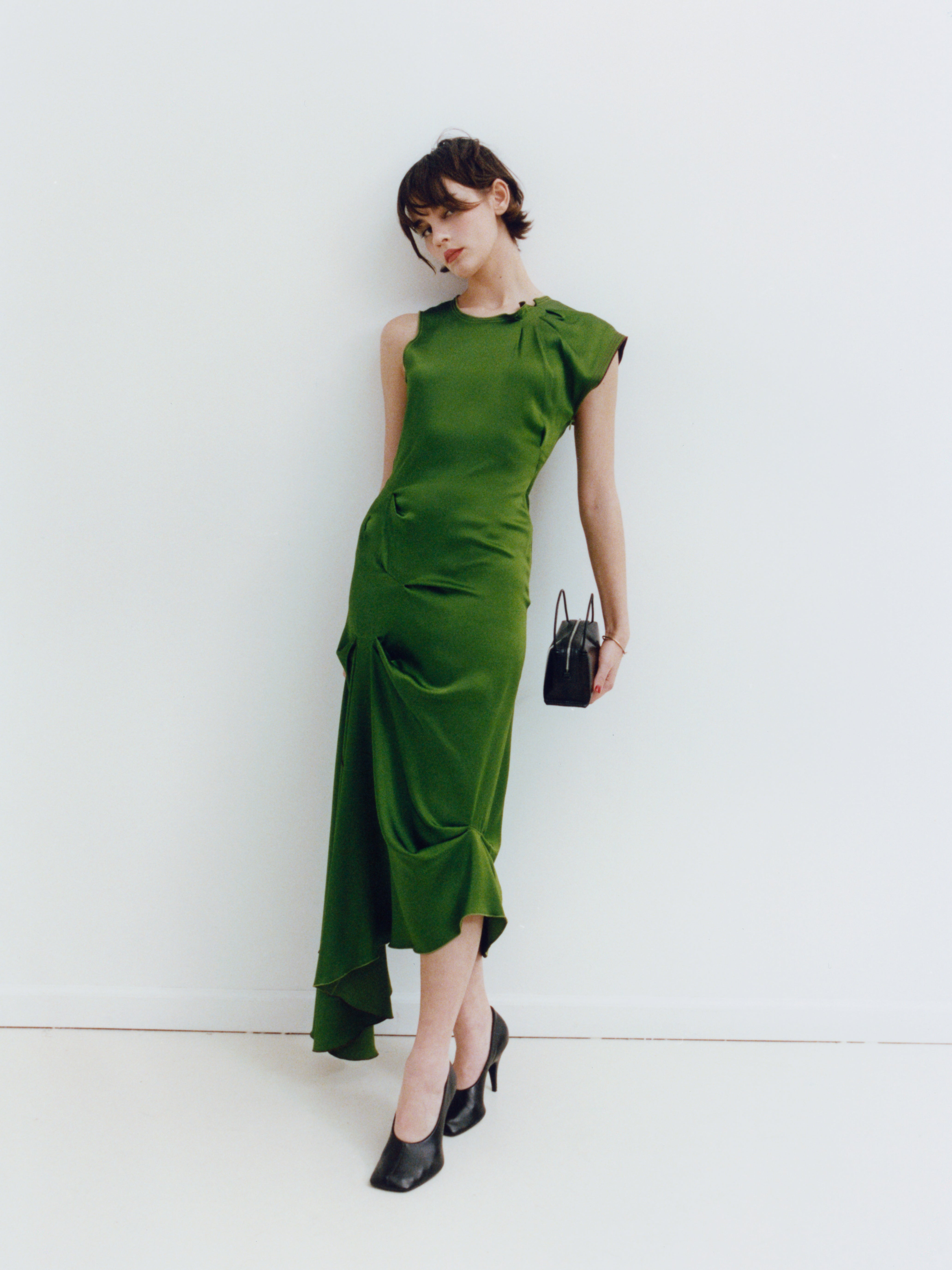 Woman wearing a green dress with a white background holding a Verafied New York Black Lizard Café Mini Handbag