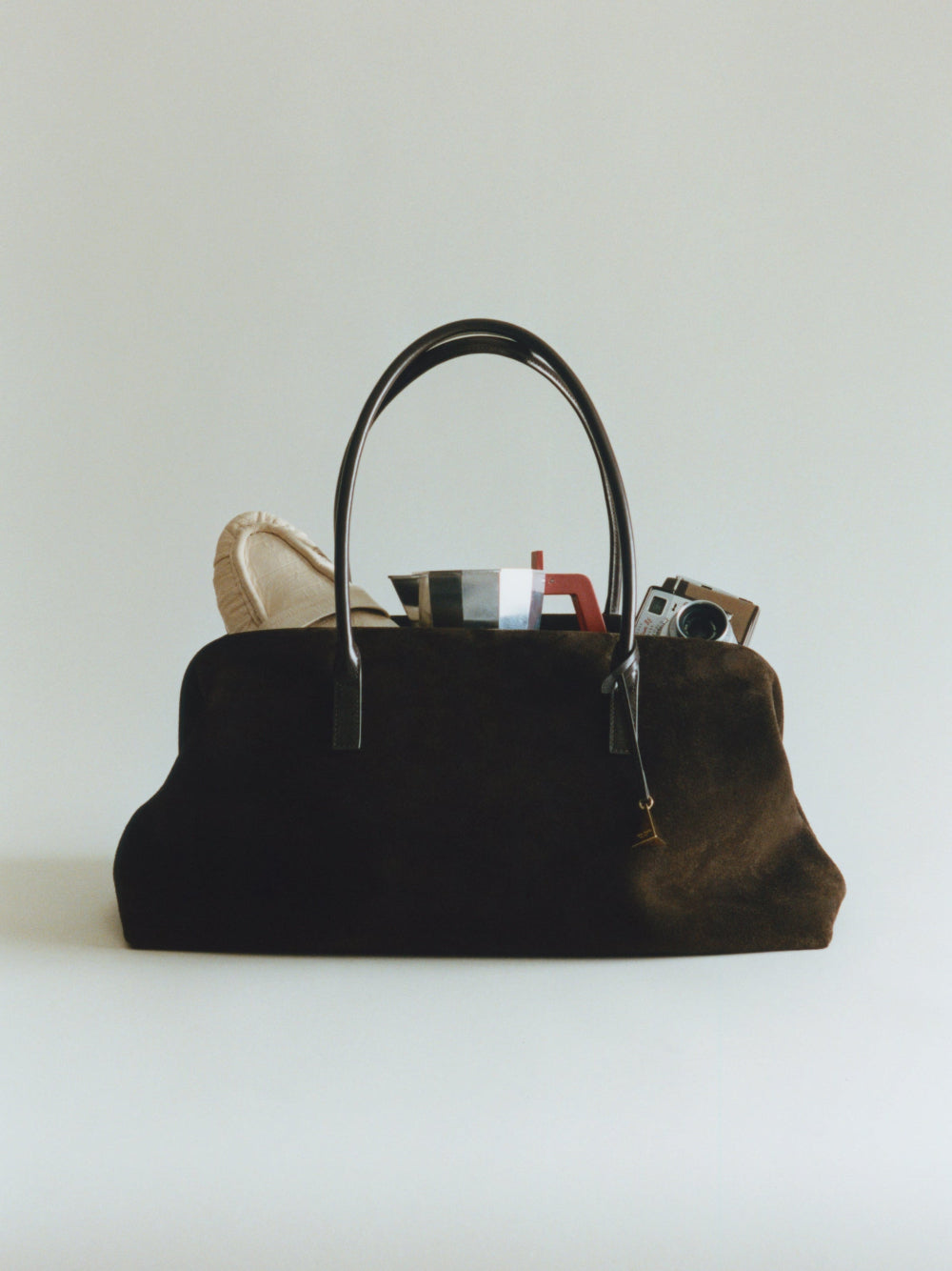 Espresso Suede Club Bag for Everyday Use with a camera and books on a light gray background