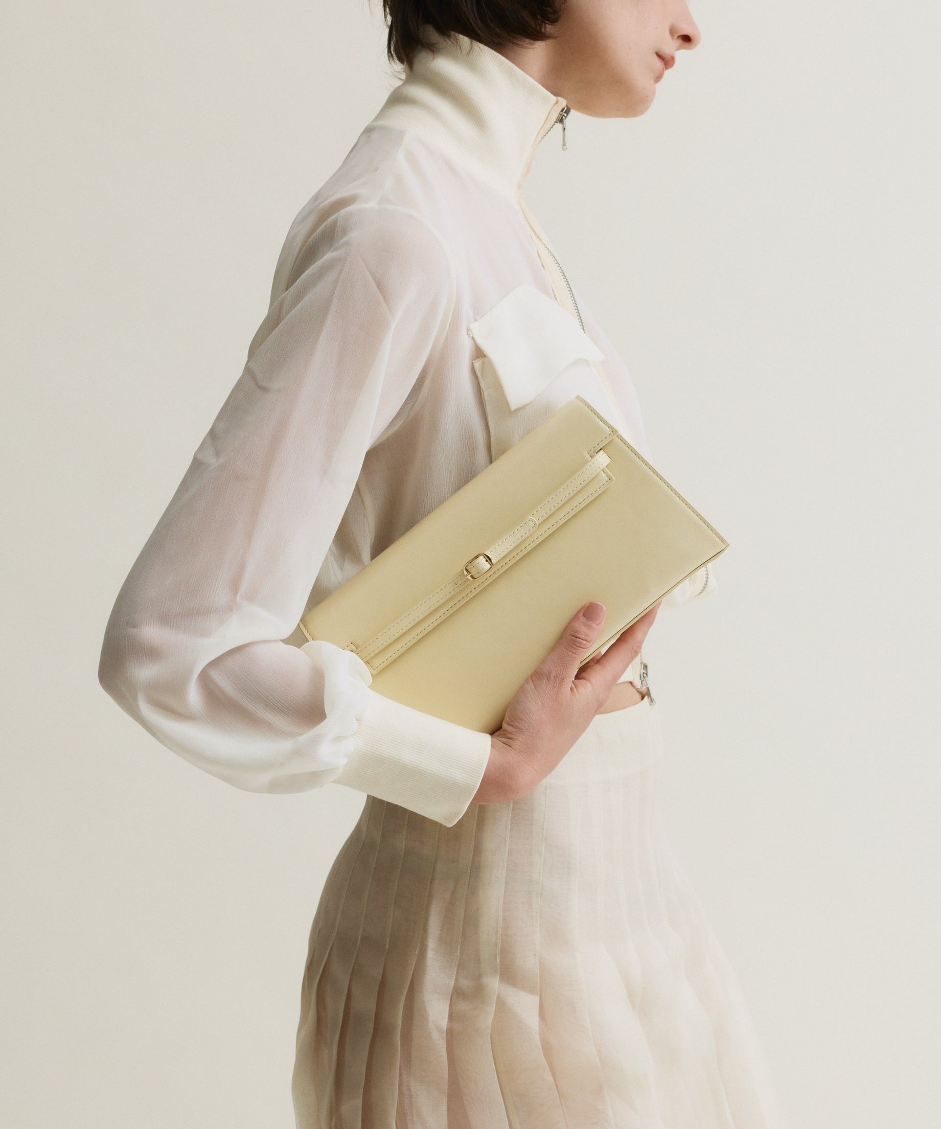 Woman holding a Butter Shoulder Purse Handbag against a plain background