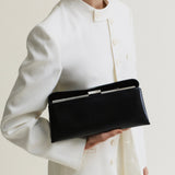 Person wearing a white outfit holding a Silver Noir Éclair Bag: Black Clutch Handbag against a plain background