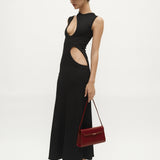 Woman wearing a black dress with cut-out design, holding a Dark Cherry Shoulder Purse Handbag on a white background