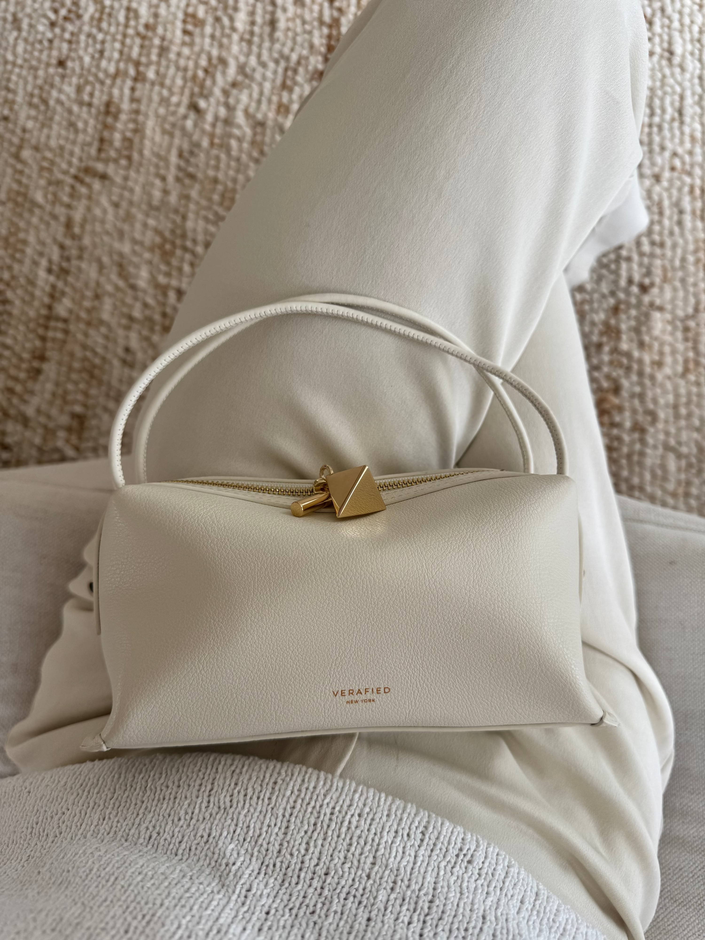 Beige Ivory Café Mini Crossbody Handbag with gold zipper on a textured surface