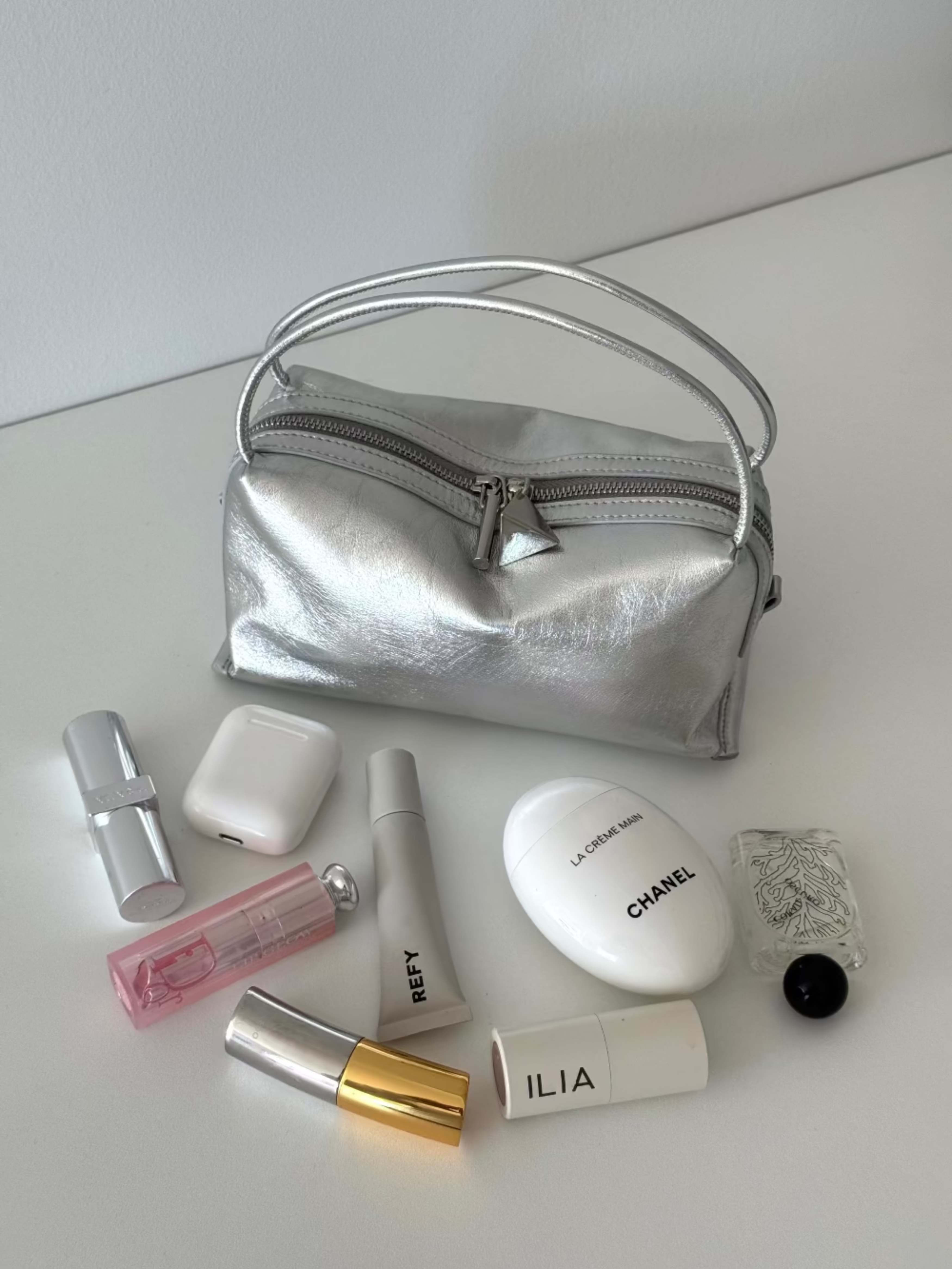 Silver Metallic Café Mini Crossbody Handbag with various beauty products on a white background