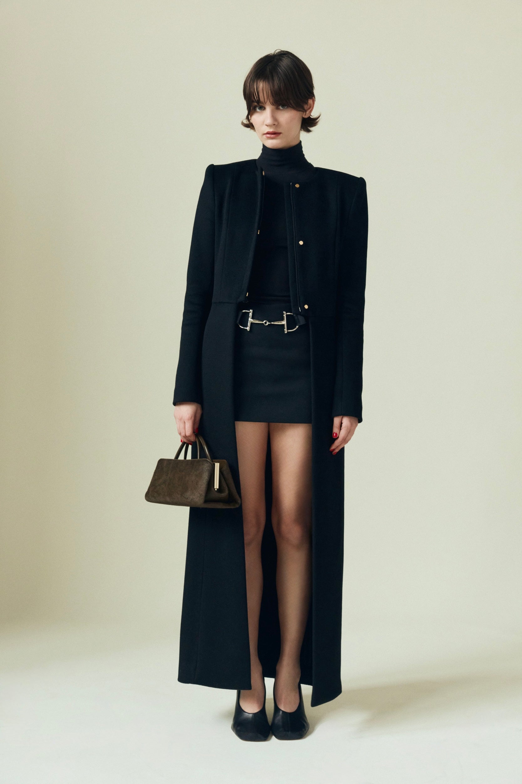 Woman in a black outfit holding a Olive Calf Hair Clutch Shoulder Handbag against a plain background