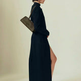 Woman wearing a long black dress with a slit, holding a Olive Calf Hair Clutch Shoulder Handbag against a plain background