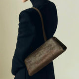Person wearing a dark coat with a Olive Calf Hair Clutch Shoulder Handbag on a beige background
